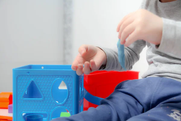 Niño pequeño de tres años se sienta en la mesa y juega con plas —  Fotos de Stock