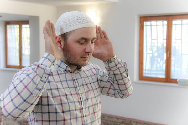 Young muslim man praying inside of beautiful mosque