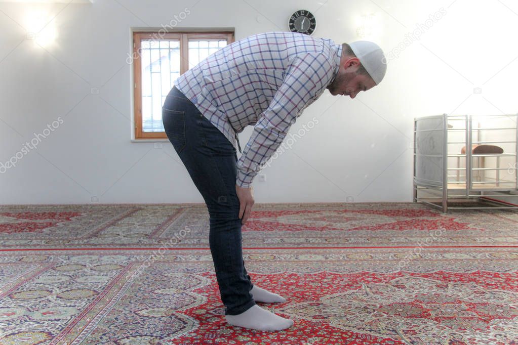 Young muslim man praying inside of beautiful mosque