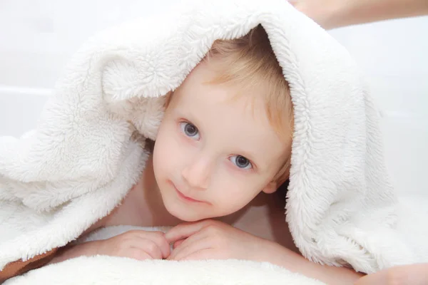 Schöner Junge schaut unter Decke hervor — Stockfoto