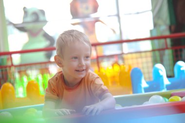 Üç yaşındaki küçük çocuk oyun parkında eğleniyor.