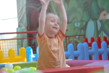 Üç yaşındaki küçük çocuk oyun parkında eğleniyor.