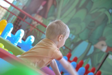 Üç yaşındaki küçük çocuk oyun parkında eğleniyor.