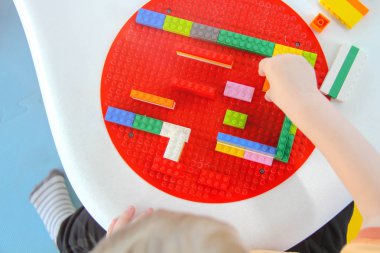 Üç yaşındaki küçük çocuk oyun parkında eğleniyor.