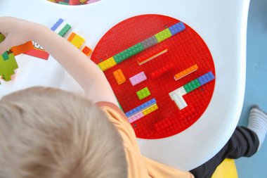 Üç yaşındaki küçük çocuk oyun parkında eğleniyor.