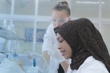 Laboratuvarda deney yapan çok ırklı iki genç kadın bilim adamı.