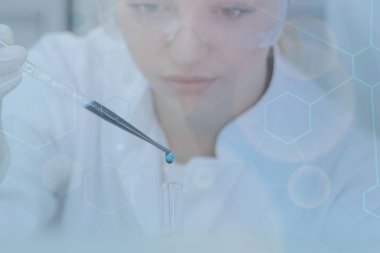 Genç kadın bilim adamı laboratuarda deneyler yapıyor.