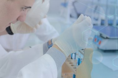 Genç erkek bilim adamı laboratuarda deneyler yapıyor.