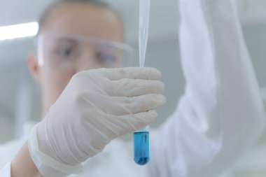 Genç kadın bilim adamı laboratuarda deneyler yapıyor.