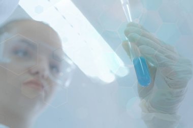 Laboratuvarda test tüpleriyle çalışan genç kadın laboratuvar bilim adamı.