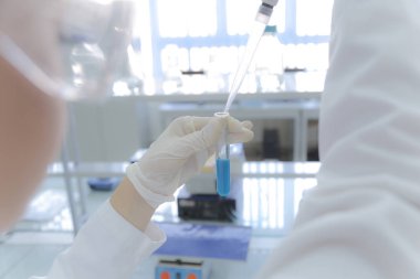 Laboratuvarda test tüpleriyle çalışan genç kadın laboratuvar bilim adamı.