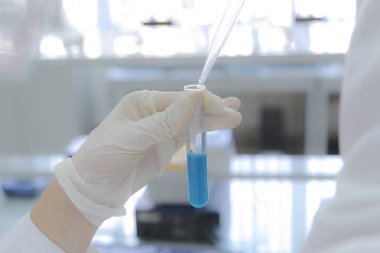 Laboratuvarda test tüpleriyle çalışan genç kadın laboratuvar bilim adamı.