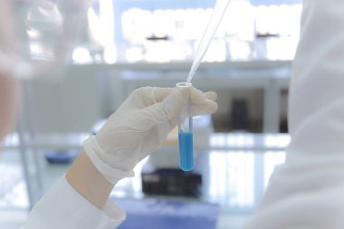 Laboratuvarda test tüpleriyle çalışan genç kadın laboratuvar bilim adamı.