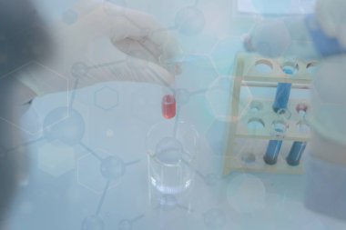 Laboratuvarda deney tüpleriyle çalışan genç bir bilim adamı.