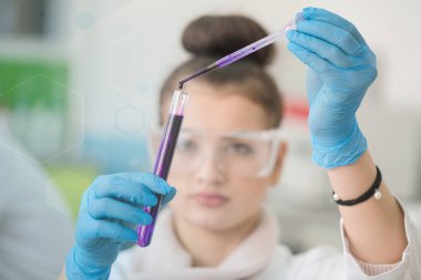 Laboratuvarda test tüpleriyle çalışan genç kadın laboratuvar bilim adamı.