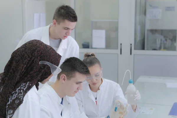 Group of young  scientists doing experiments in laboratory — Stock Photo, Image