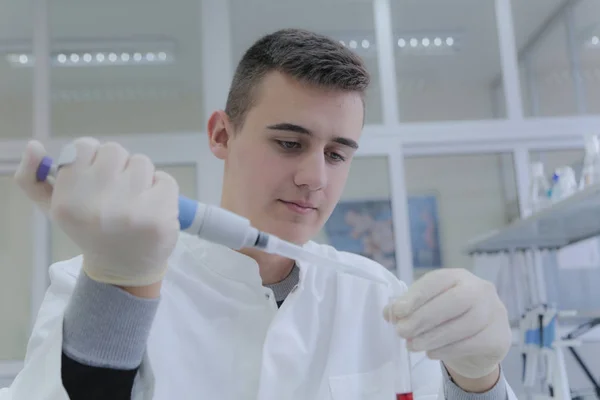 Joven estudiante científico trabajando en el laboratorio con tubos de ensayo, tes —  Fotos de Stock