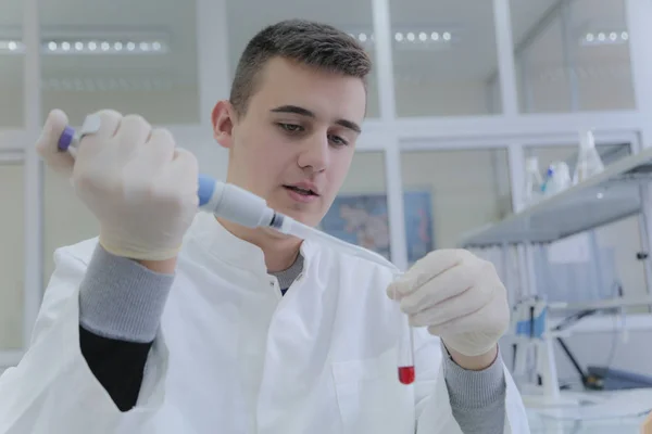 Молодой ученый-студент, работающий в лаборатории с пробирками — стоковое фото