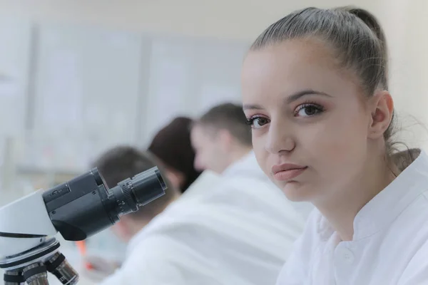 Jeune femme scientifique regardant à travers un microscope dans un laboratoire — Photo