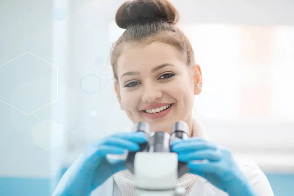 Jonge vrouwelijke wetenschapper kijkt door een microscoop in een laboratorium — Stockfoto