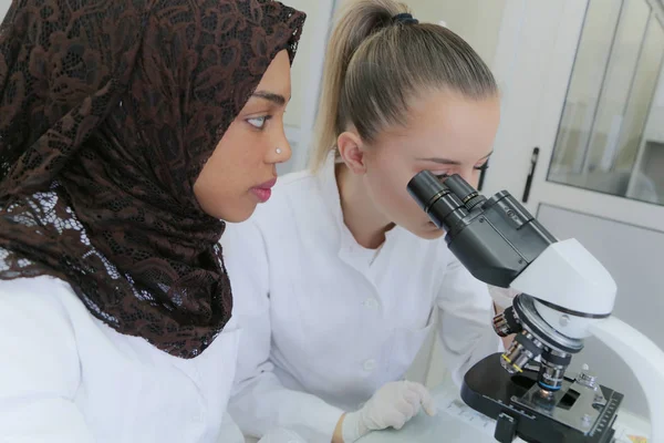 Dwie wielonarodowe młode kobiety-naukowcy robiące eksperymenty w laboratorium — Zdjęcie stockowe