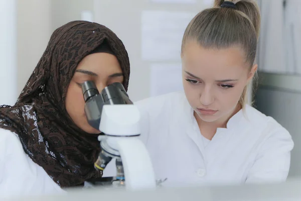 Dwie wielonarodowe młode kobiety-naukowcy robiące eksperymenty w laboratorium — Zdjęcie stockowe