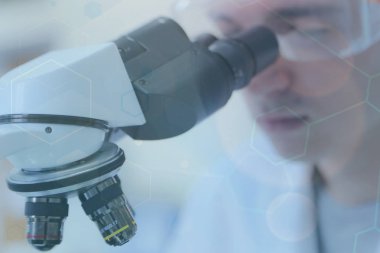 Genç bilim adamı bir laboratuarda mikroskoptan bakıyor.