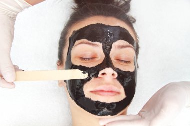 Siyah kömür maskesi takan genç ve güzel bir kadın. Deri 