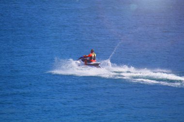 Yaz tatili boyunca jet ski ile dalgaları yöneten genç adam.
