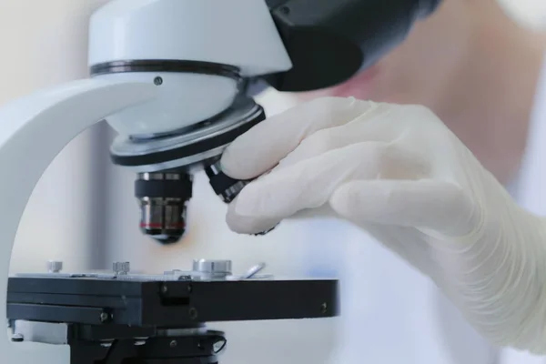 Joven científico masculino mirando a través de un microscopio en un laboratorio — Foto de Stock