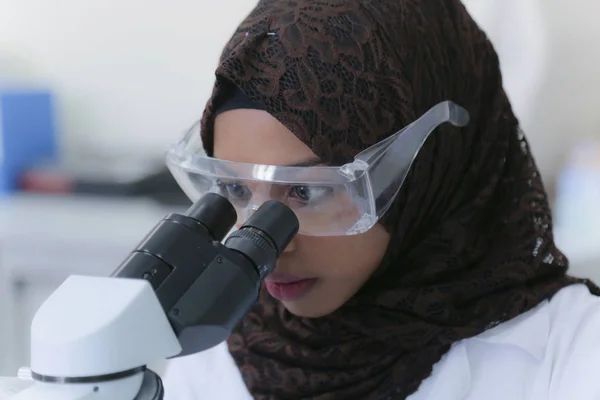 Młoda afrykańska muzułmanka naukowiec patrząc przez mikroskop — Zdjęcie stockowe