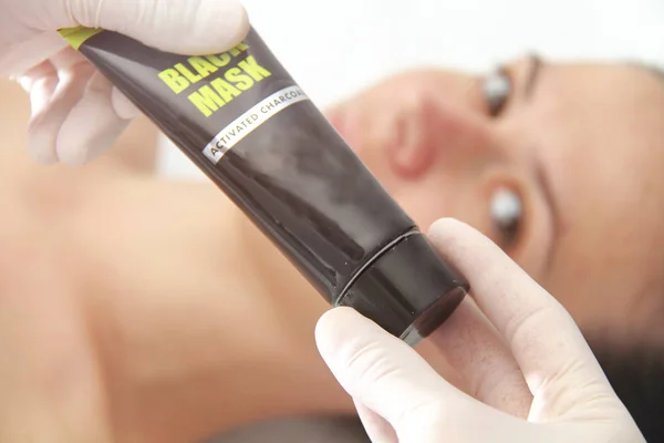 Young beautiful woman applying black charcoal facial mask. Skin — Stock Photo, Image