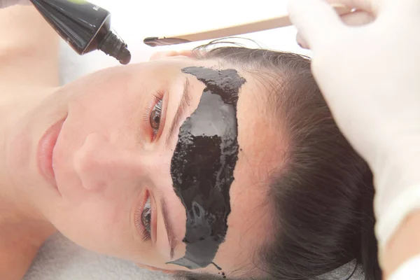 Young beautiful woman applying black charcoal facial mask. Skin — Stock Photo, Image