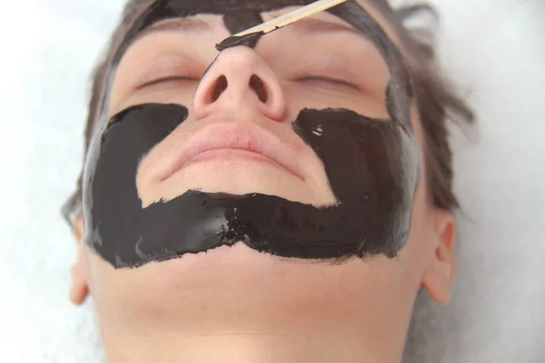 若い美しい女性黒炭顔マスクを適用します。皮膚 — ストック写真