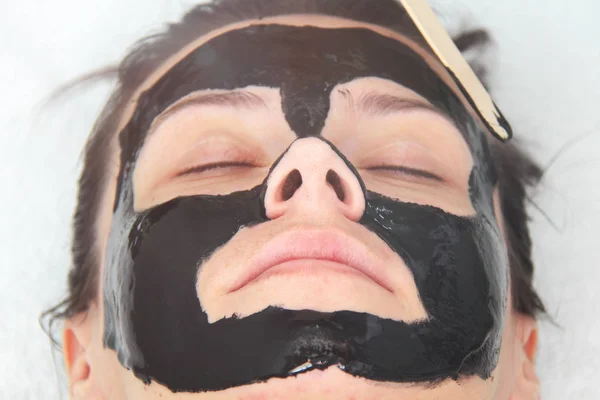 Mladá krásná žena nanáší černé uhlí obličejové masky. Vzhled — Stock fotografie