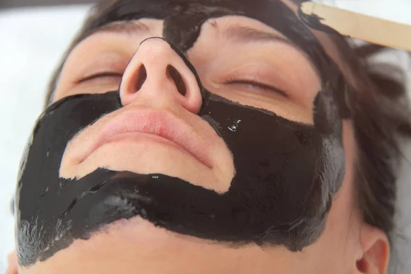 Mujer joven hermosa que aplica la máscara facial de carbón negro. Piel —  Fotos de Stock