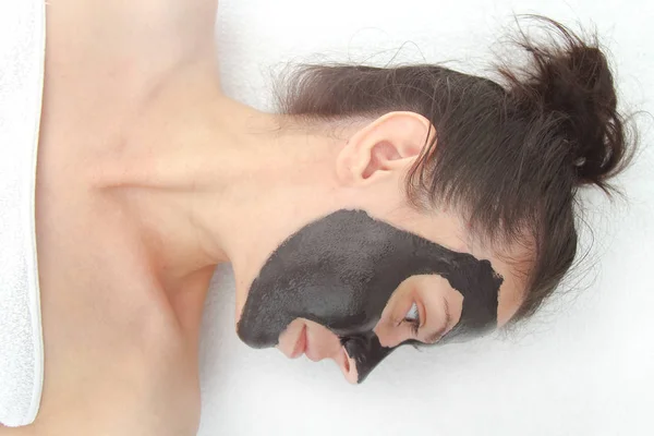 Mladá krásná žena nanáší černé uhlí obličejové masky. Vzhled — Stock fotografie