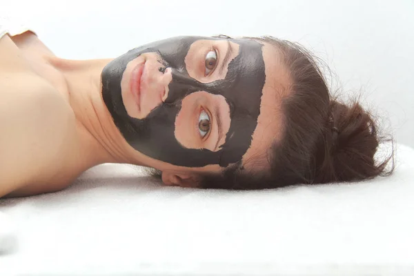 Jeune belle femme appliquant un masque facial au charbon de bois noir. Peau — Photo