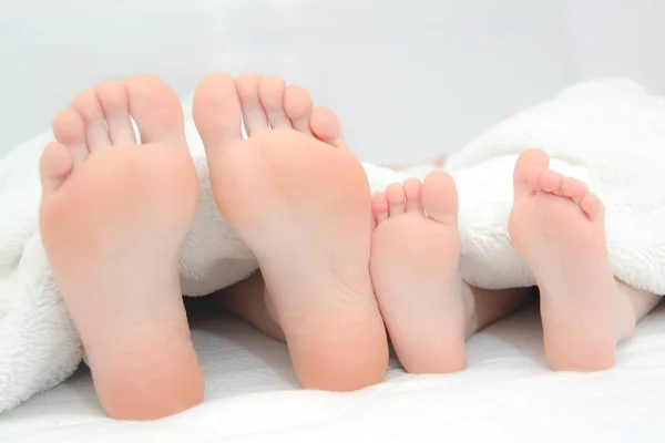 Mother and little son  laying on bed, their feets on focus — Stock Photo, Image