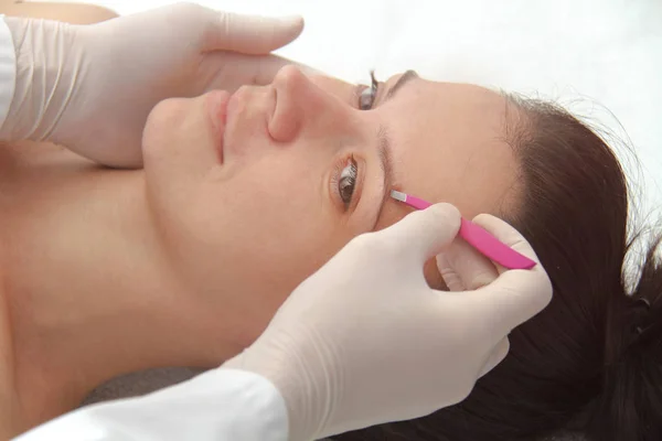 Ung kvinna med professionell ögonbrynskorrigering förfarande i — Stockfoto