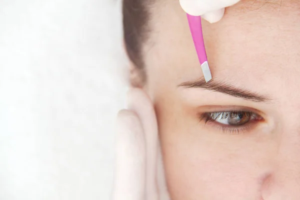 Mujer joven que tiene procedimiento profesional de corrección de cejas en — Foto de Stock