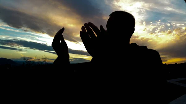Silhueta de jovem muçulmano rezando durante o pôr do sol — Fotografia de Stock