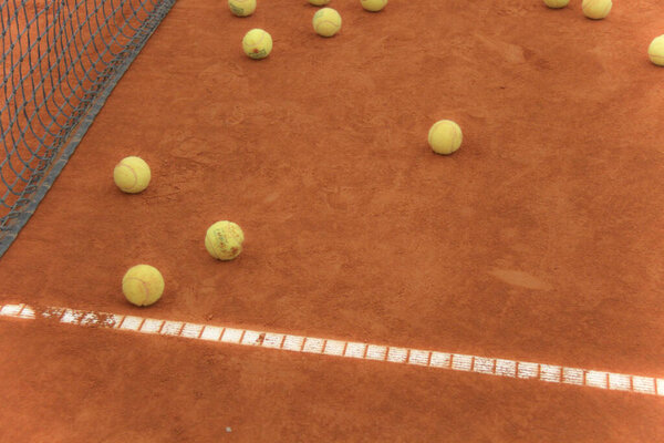 Tennis balls on red court with gray net