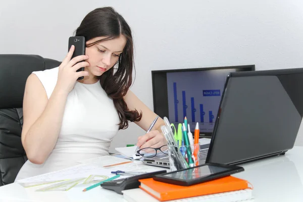 Atractiva mujer de negocios usar el teléfono inteligente y sentarse en su varita —  Fotos de Stock