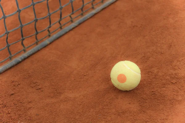 Tennisballen op rode baan met grijs net — Stockfoto