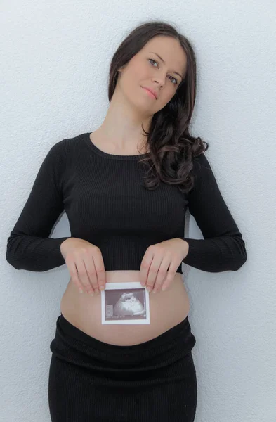 Счастливая беременная женщина с большим животом у окна, беременность, мать — стоковое фото