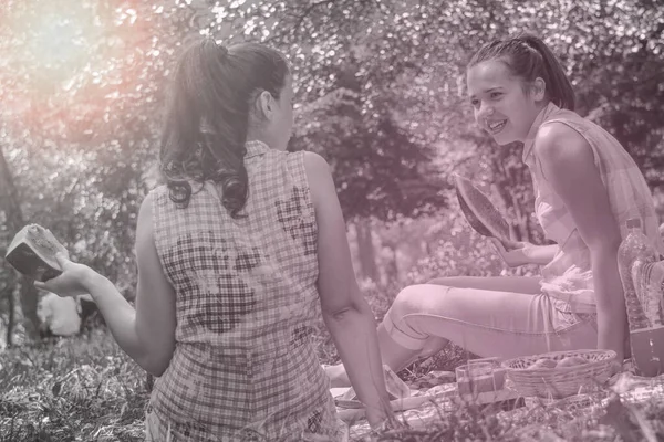 Twee jonge vrouwen genieten van gesprek en het eten van watermeloen op — Stockfoto