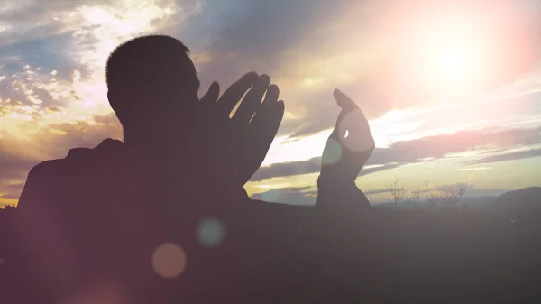 Silhueta de jovem muçulmano rezando durante o pôr do sol — Fotografia de Stock