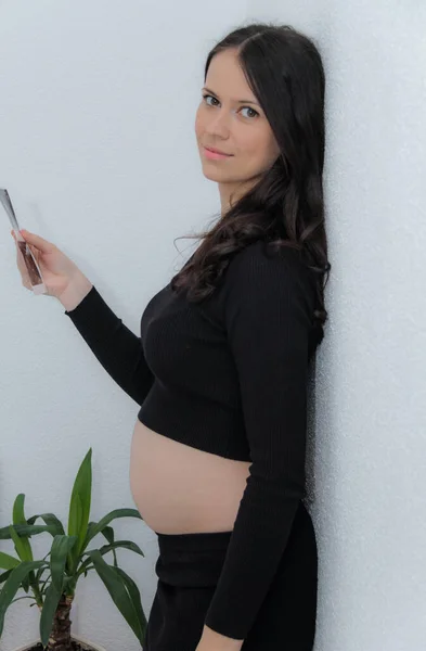 Gelukkig zwangere vrouw met grote buik bij het raam, zwangerschap, moeder — Stockfoto