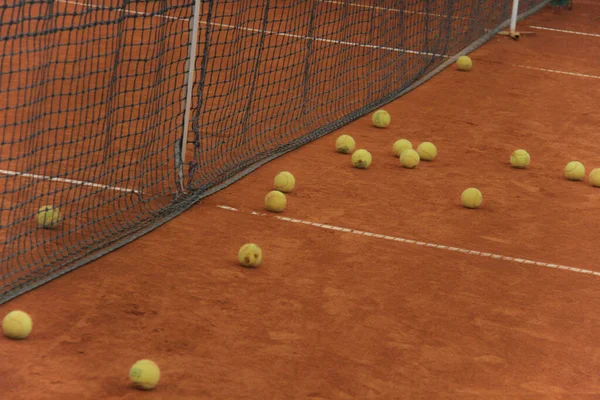 Tennisballen op rode baan met grijs net — Stockfoto